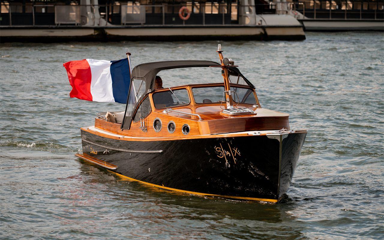 Coque noire et cabine en bois verni du SAX Boat, logo SAX à la proue, sur la Seine