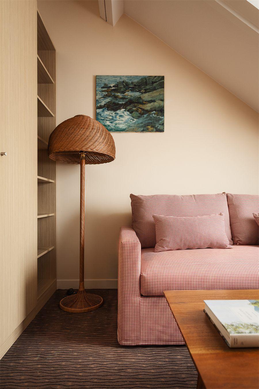Coin salon d'une chambre, canapé en vichy rouge et lampadaire en rotin