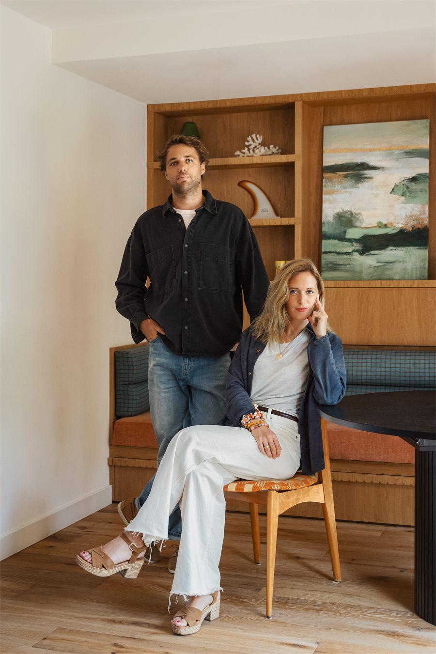 Jeremy et Flore Gosse dans le salon de leur hôtel, dérive de surf posée sur l'étagère