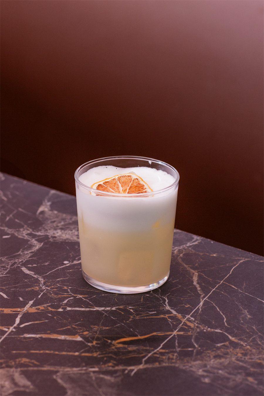 Cocktail signature de Suki Paris, mousse et agrume séché, sur marbre sombre