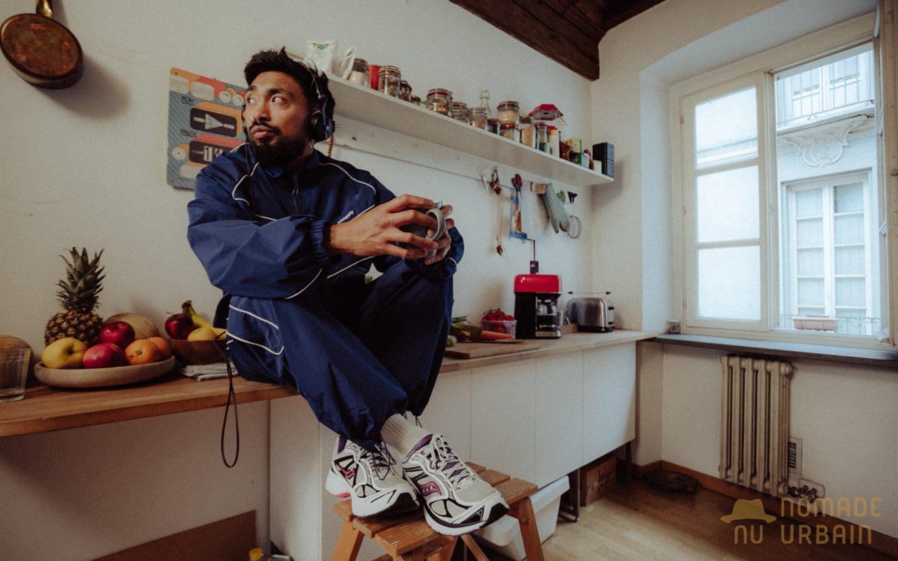 Homme en survêtement bleu assis dans une cuisine, chaussé de la Saucony ProGrid Guide 7 White/Drupe