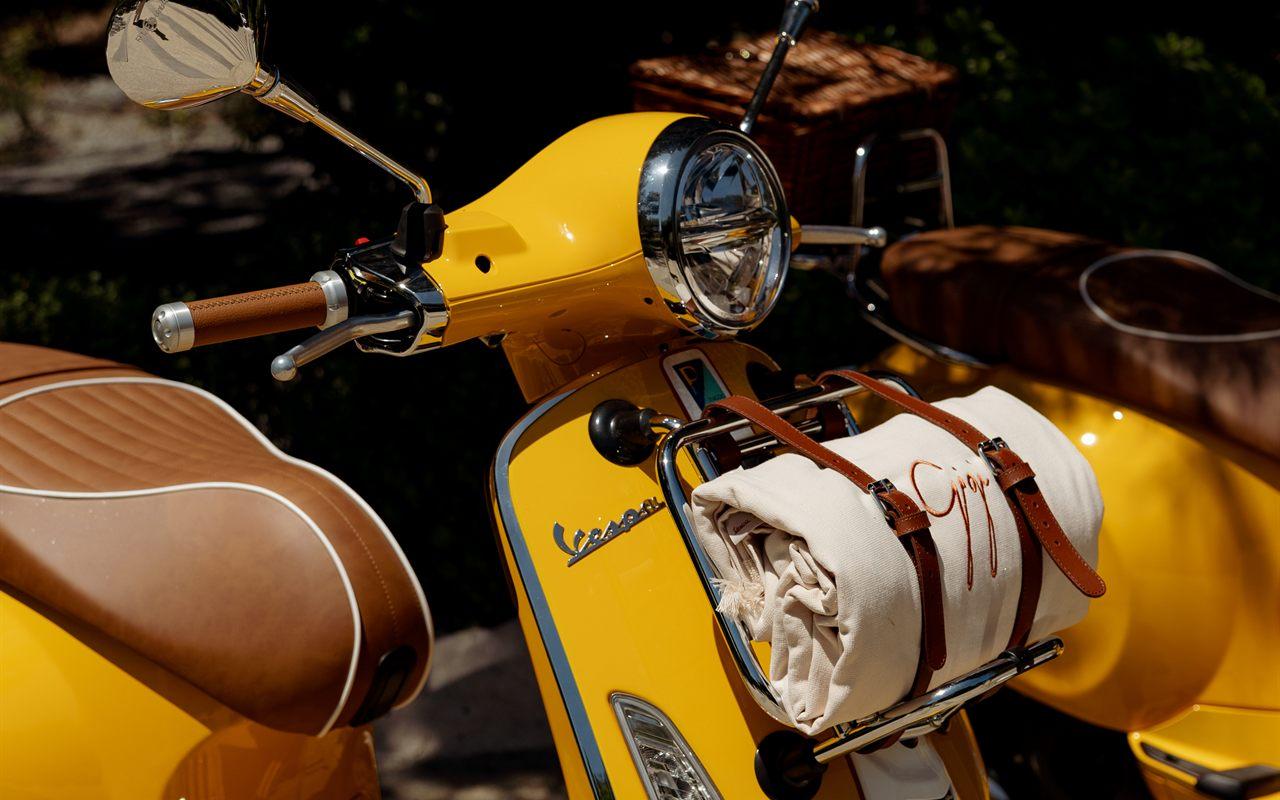 Détail de la Vespa Gigi : selle en cuir cognac et serviette de plage Gigi sur le porte-bagages