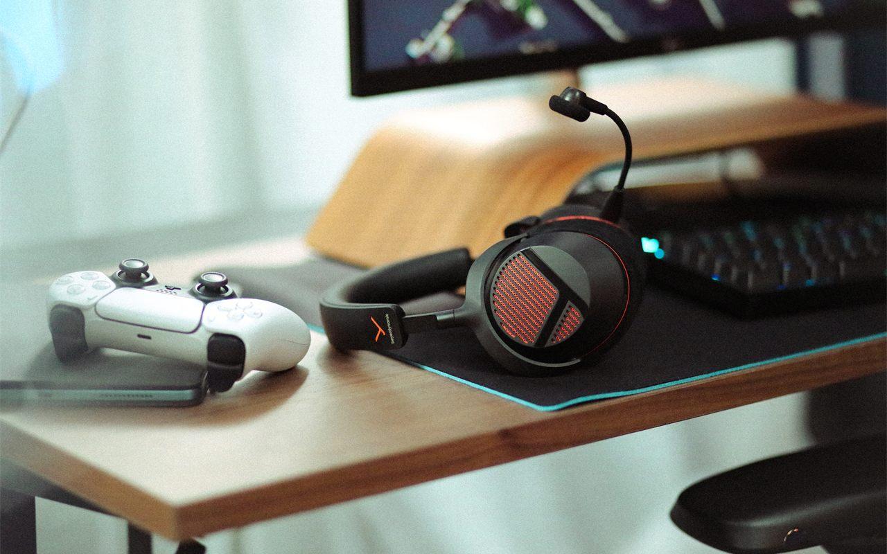 Casque beyerdynamic MMX 130 sans fil noir posé sur un bureau, micro déployé, manette et clavier