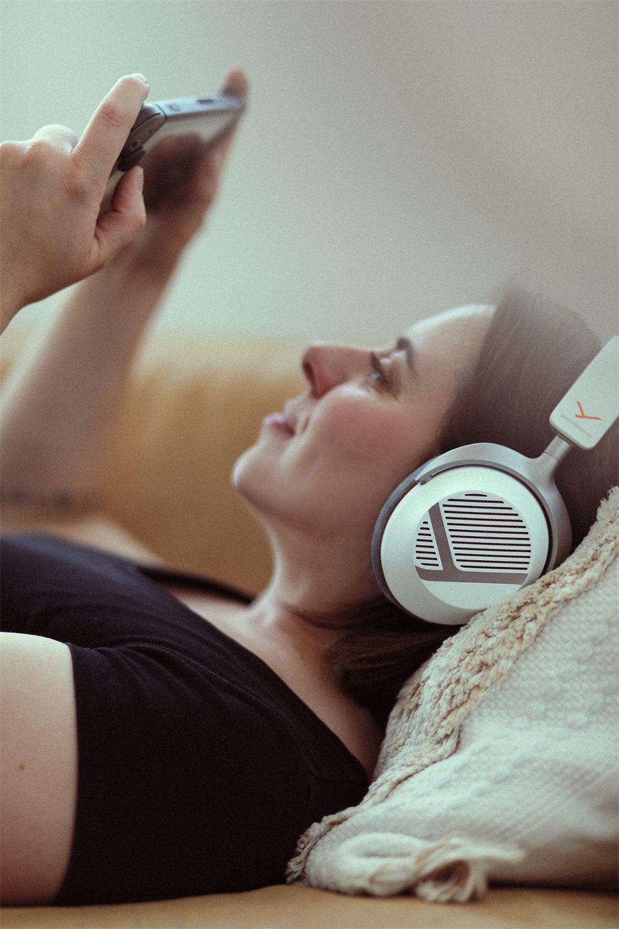 Joueuse allongée sur un canapé avec le casque beyerdynamic MMX 130 sans fil