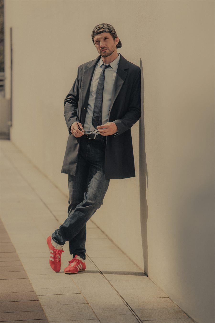 Manteau long porte sur un costume et un jean