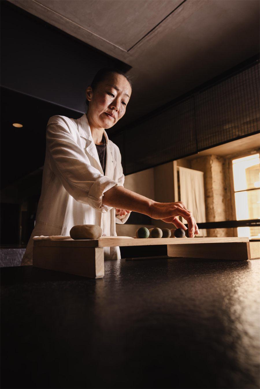 Miki Ishii aligne les hitokuchigashi sur une planche de bois clair
