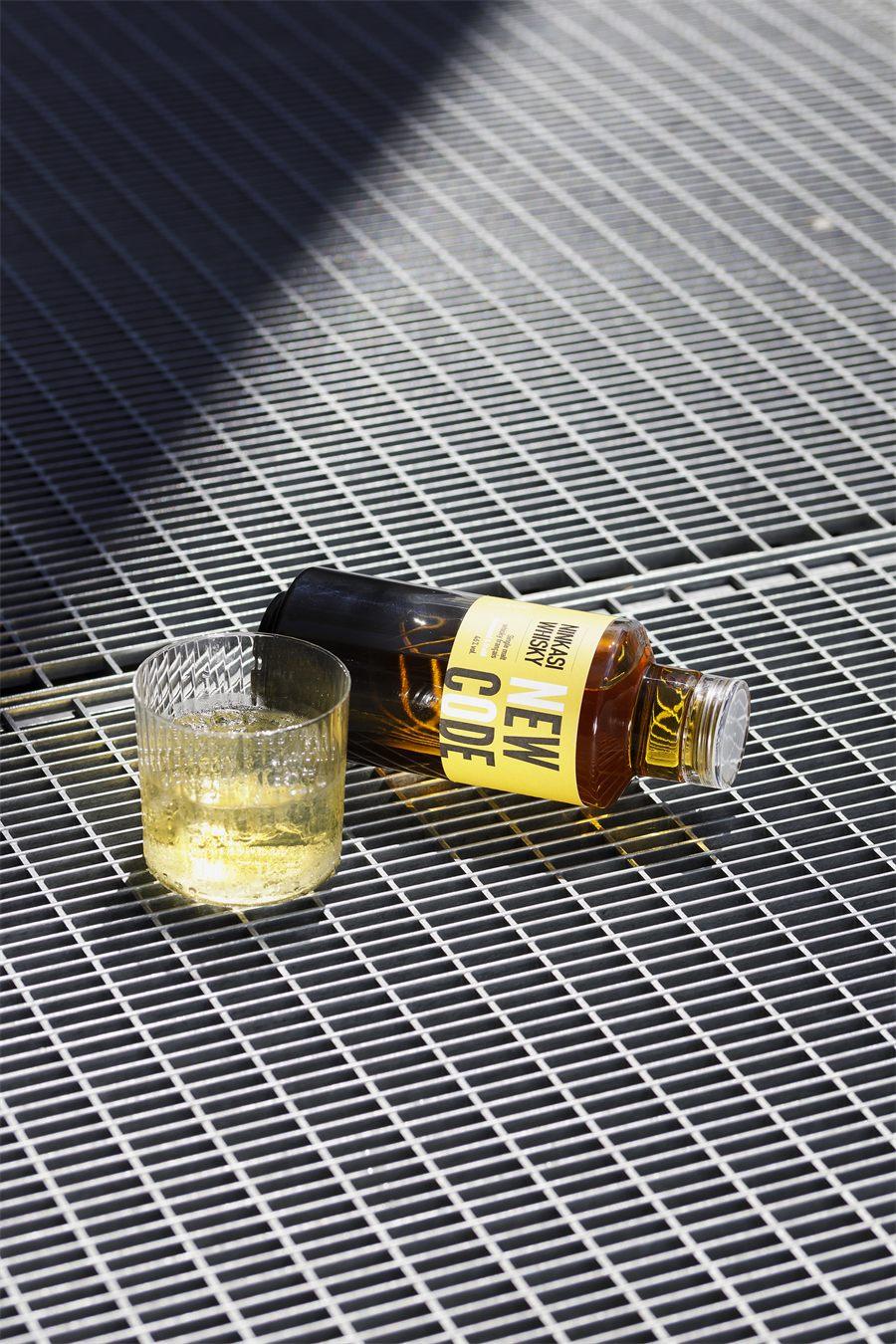 Le whisky Ninkasi New Code pose pres d'un verre servi, au soleil