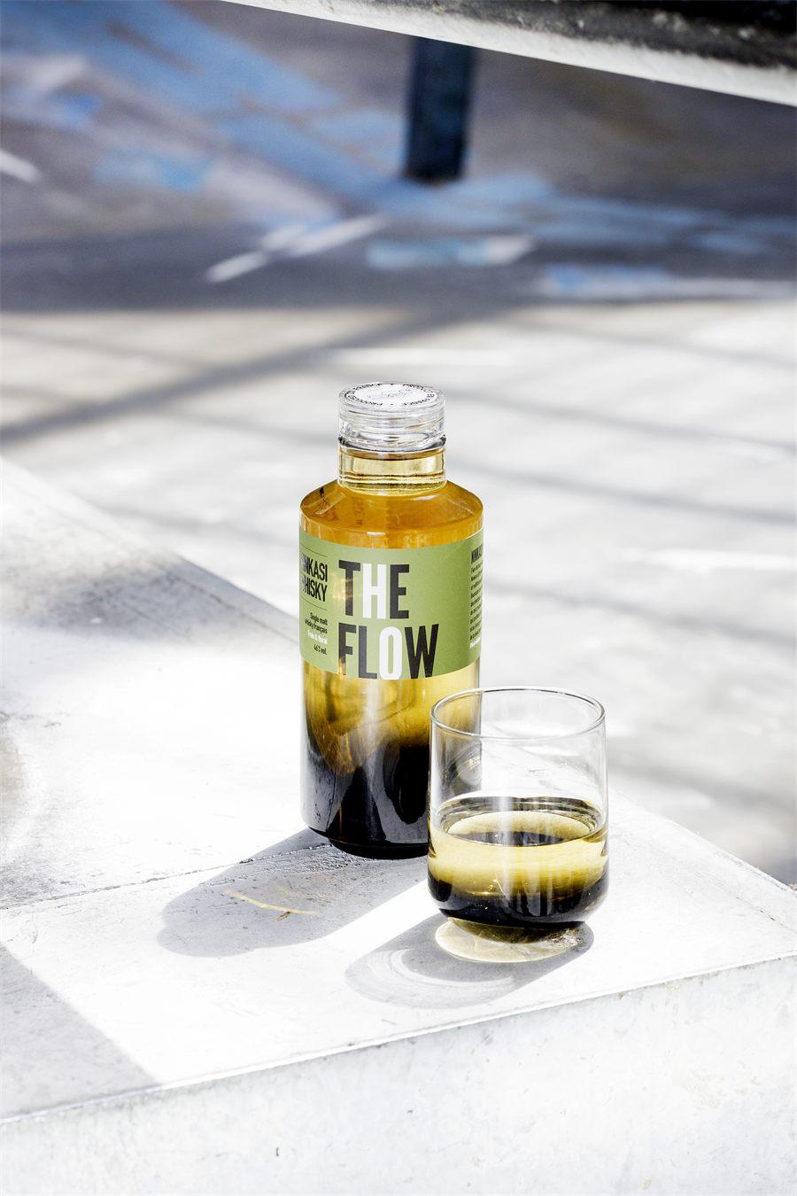 La bouteille Ninkasi Whisky The Flow et son verre sur des marches ensoleillees