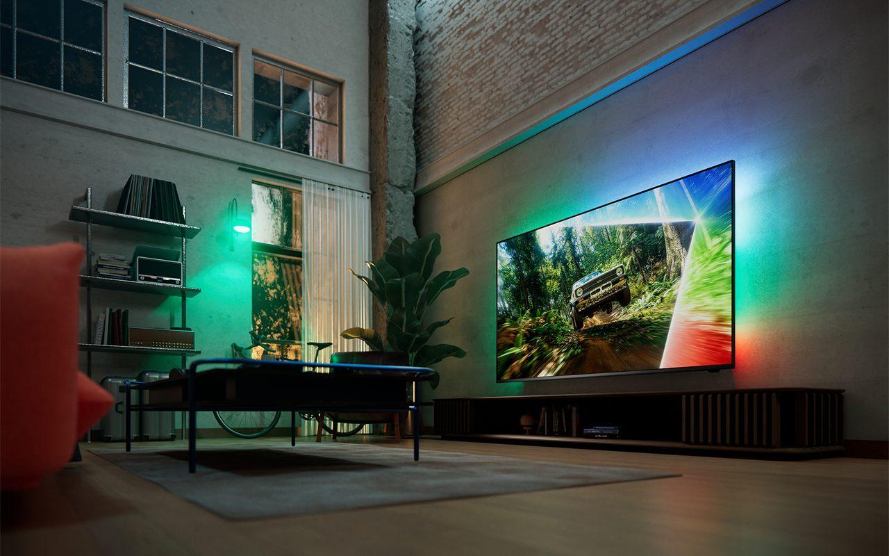 Televiseur Philips MLED981 dont l'Ambilight projette ses couleurs sur le mur d'un salon