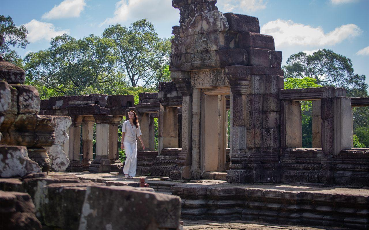 Visiteuse en tenue blanche marchant dans un temple d'Angkor sous un ciel bleu
