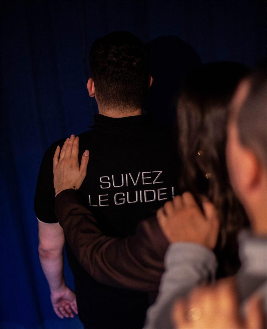 un guide en polo Suivez le guide mene un convive vers la salle plongee dans le noir