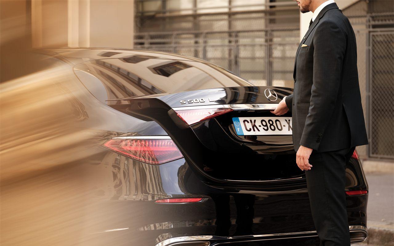 Chauffeur Wheely chargeant le coffre d'une Mercedes dans une rue de Paris