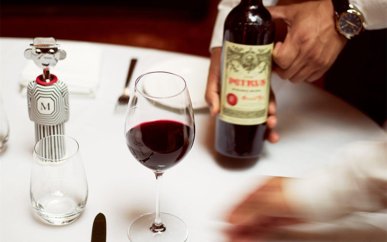 Un serveur présente une bouteille de vin rouge à côté du tire-bouchon Alessandro M.