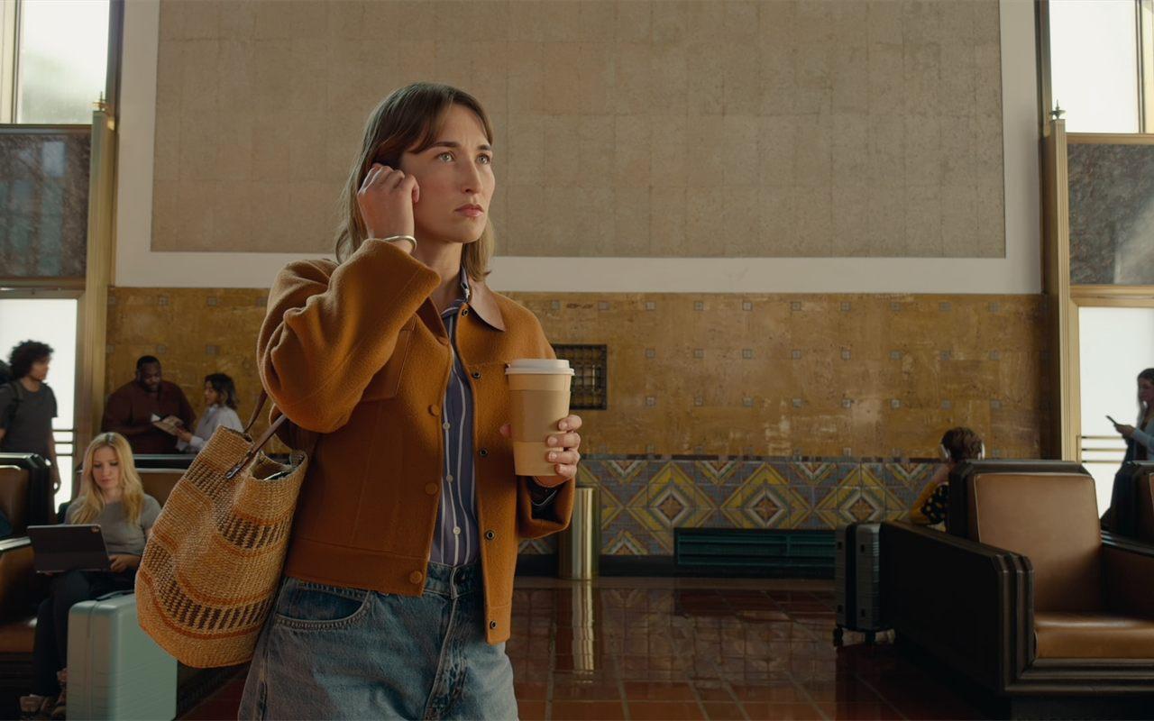 Une voyageuse porte les AirPods 5 dans le hall bruyant d'une gare