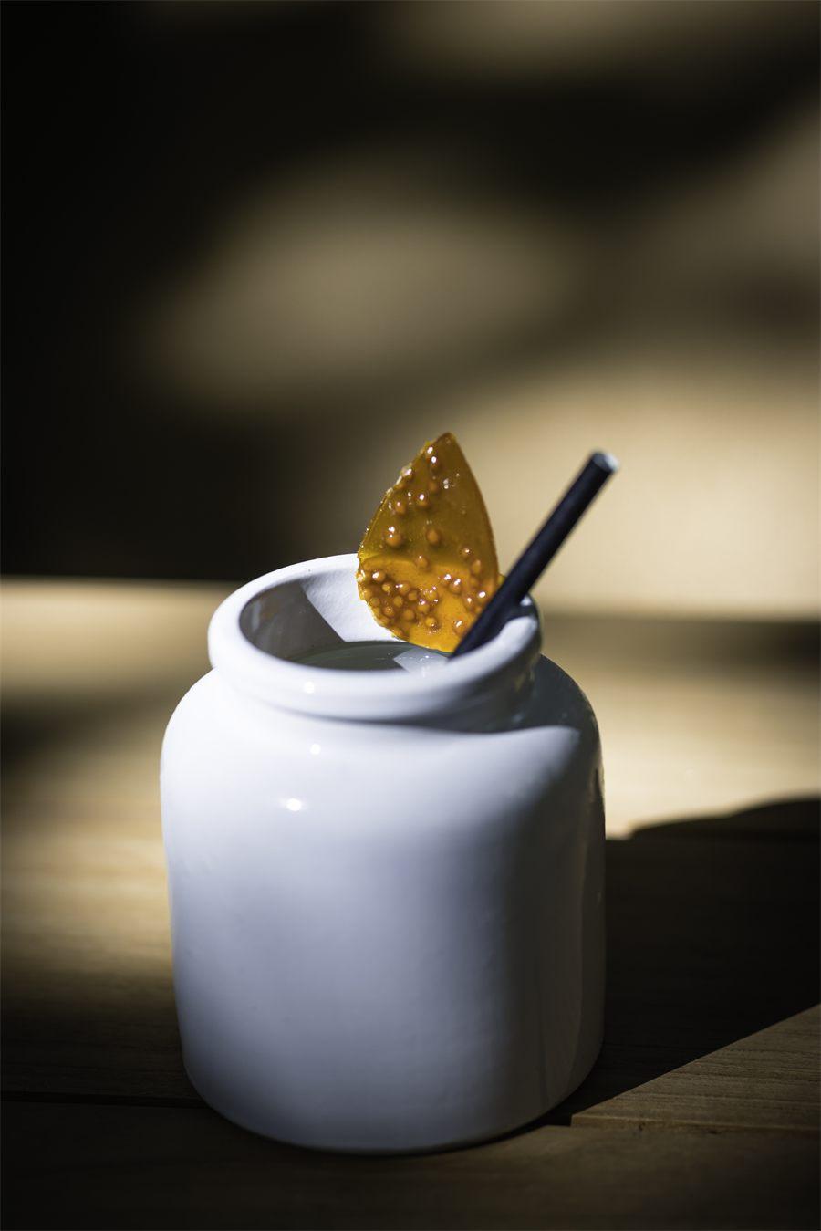 Cocktail servi dans un pot de moutarde en grès, paille et tuile caramélisée piquée de graines de moutarde