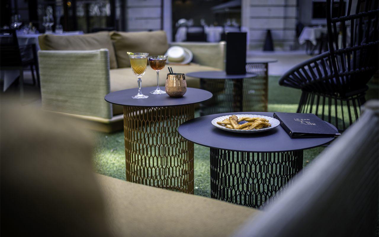 Guéridons de la terrasse du Bar by La Cloche avec cocktails et carte