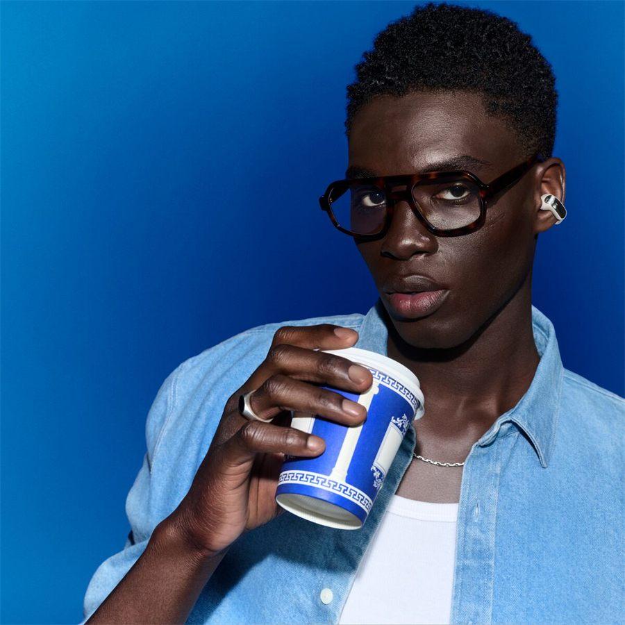 homme portant des Bose Ultra Open Earbuds avec un café à la main
