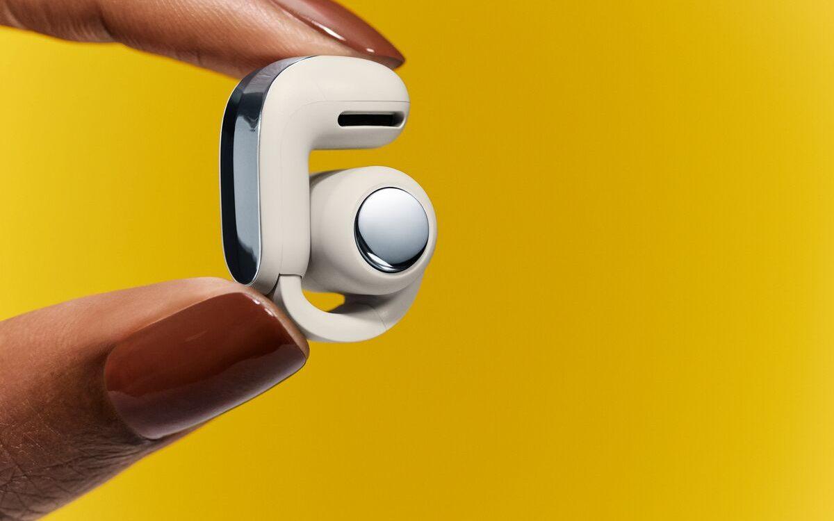 écouteur open-ear Bose Ultra tenu entre deux doigts, anneau ouvert visible
