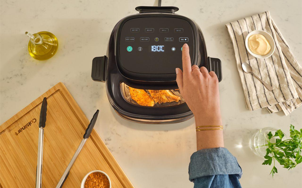 Main réglant les commandes d'un airfryer Cuisinart ClearView, aliments visibles par la fenêtre