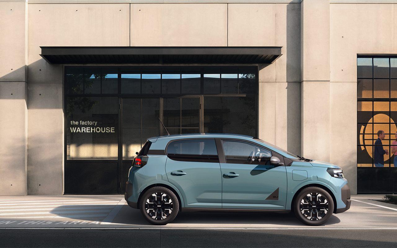 Profil de la Dacia Spring devant un bâtiment industriel, silhouette haute