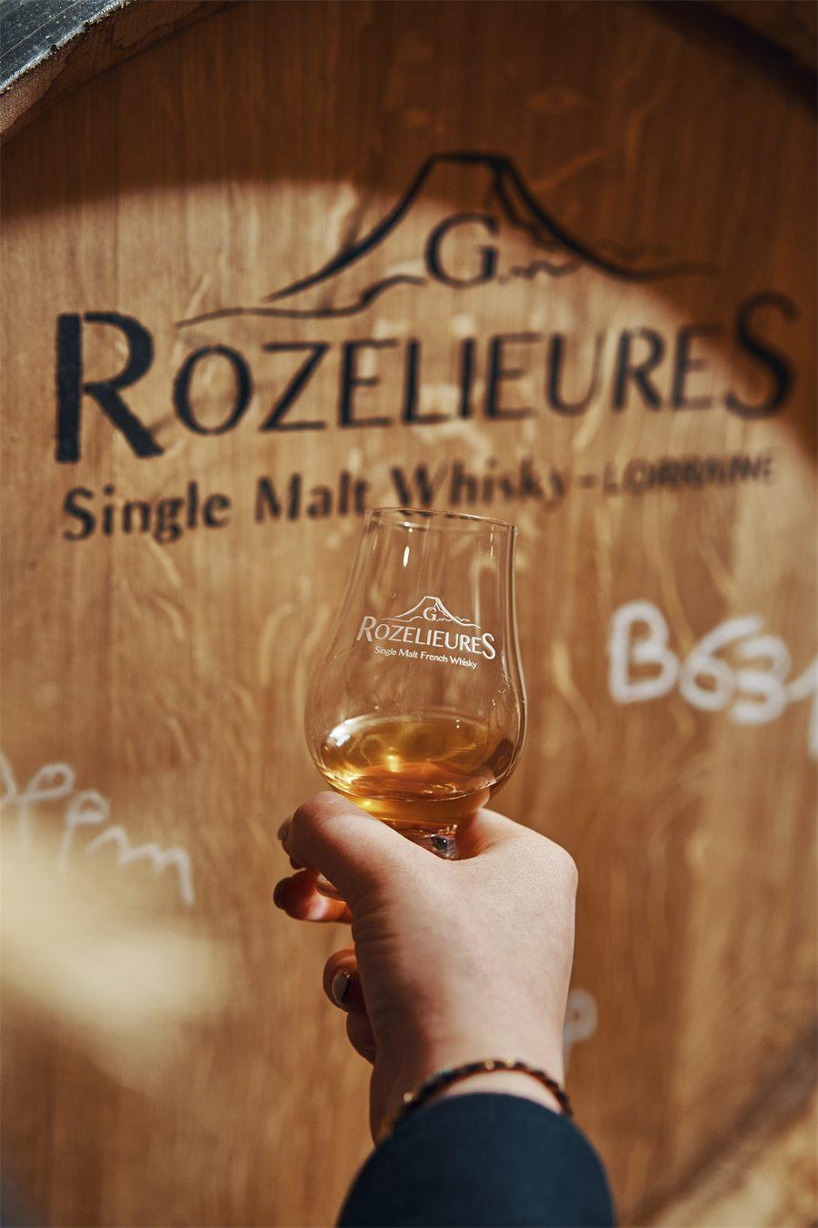 Un verre de whisky Rozelieures levé devant un fût
