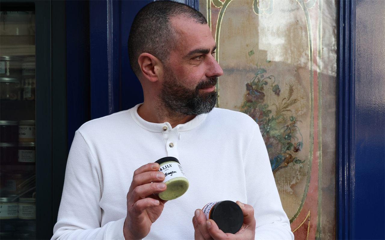 Lionel Chauvin devant la devanture bleue de sa glacerie Enzo & Lily, deux pots à la main