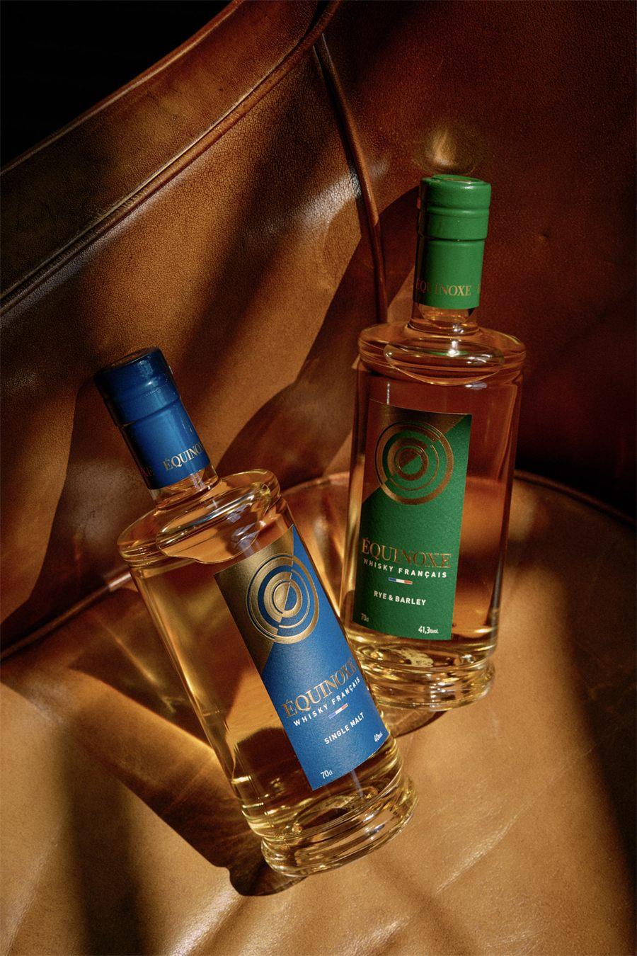 Bouteilles Équinoxe Single Malt et Rye & Barley posées sur un fauteuil en cuir fauve