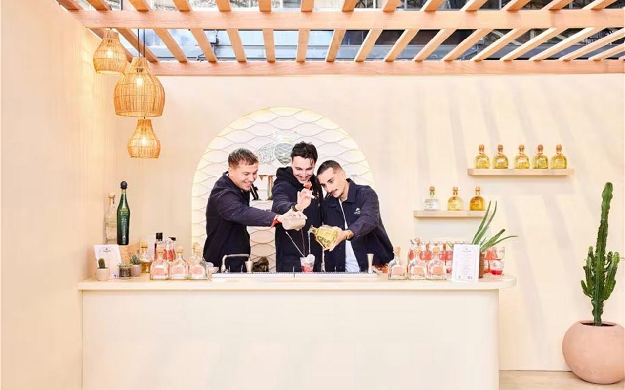 Bar éphémère en bois clair monté sur la Cocktail Street, équipe en train de servir