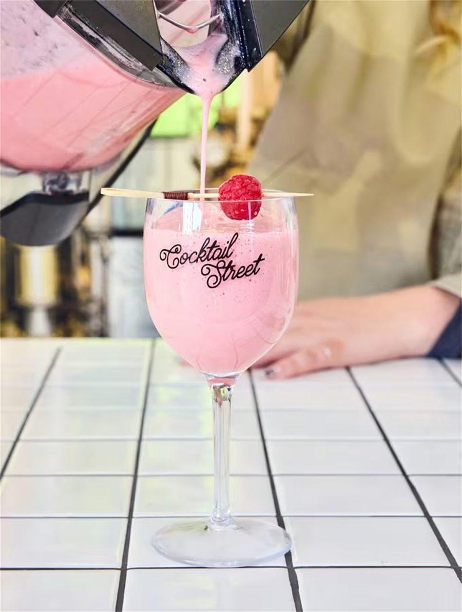 Cocktail rose à la framboise versé dans un verre siglé Cocktail Street
