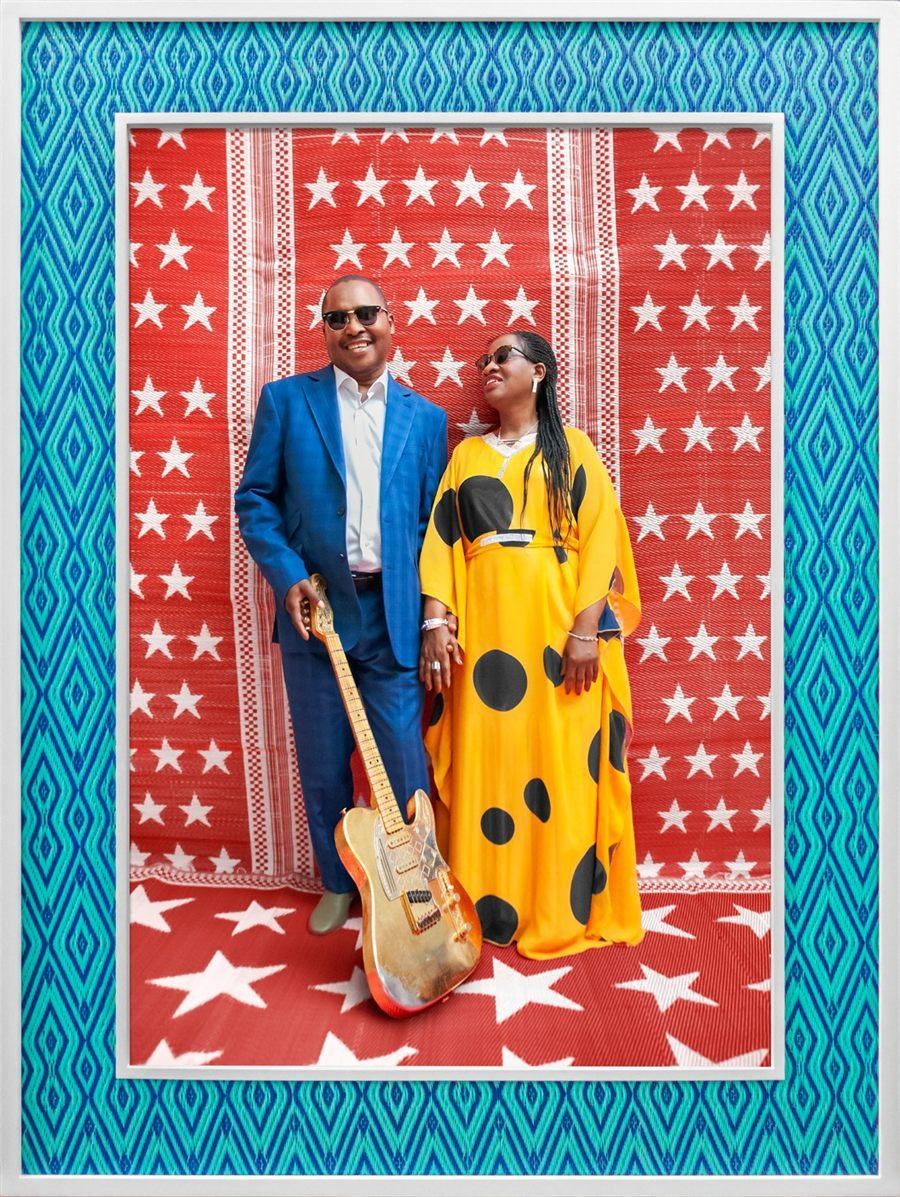 Amadou et Mariam en costume bleu et robe jaune à pois devant un fond étoilé