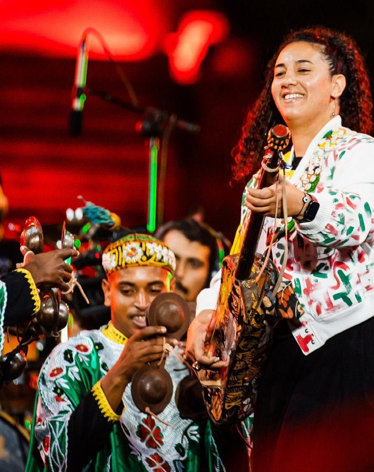 Hind Ennaira en concert, guembri en main, aux côtés d'un joueur de qraqeb