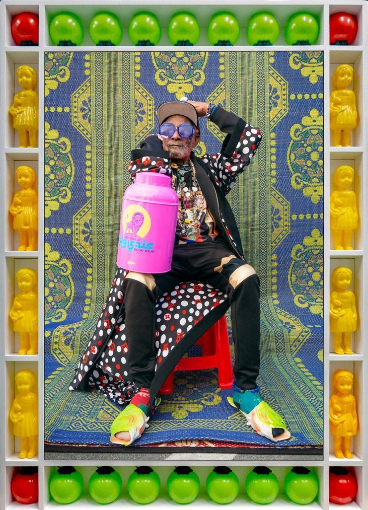 Lee Scratch Perry assis, cadre en poupées jaunes et ballons colorés