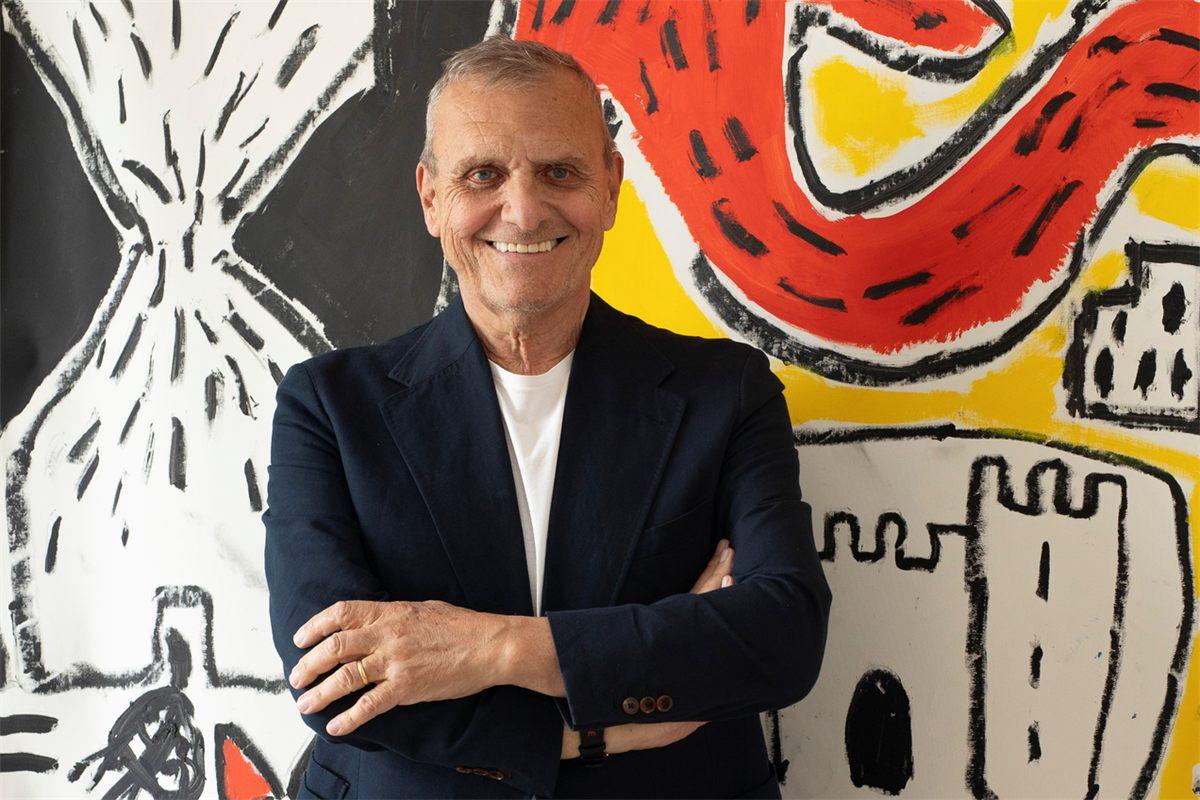 Le couturier Jean-Charles de Castelbajac, bras croisés, devant une peinture aux couleurs vives