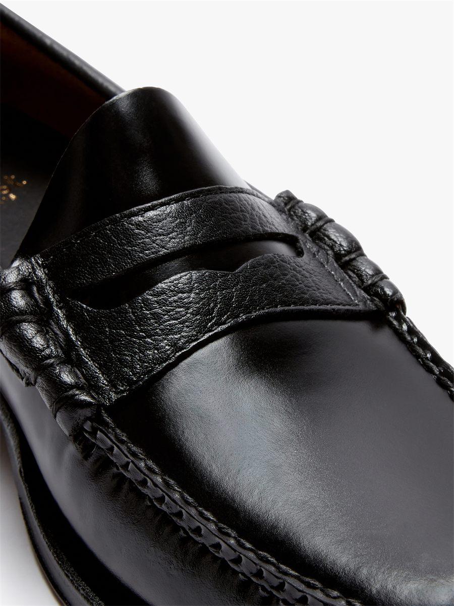 Gros plan sur le bandeau et la barrette en cuir grainé du mocassin penny noir