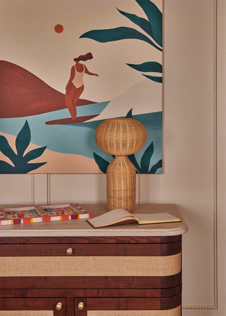 Peinture de surfeuse et lampe en rotin dans le salon de Maison Silhouette