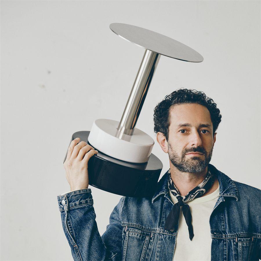 Le designer Emanuele Stamuli portant sa table d'appoint noire et blanche KONSTRUNDA