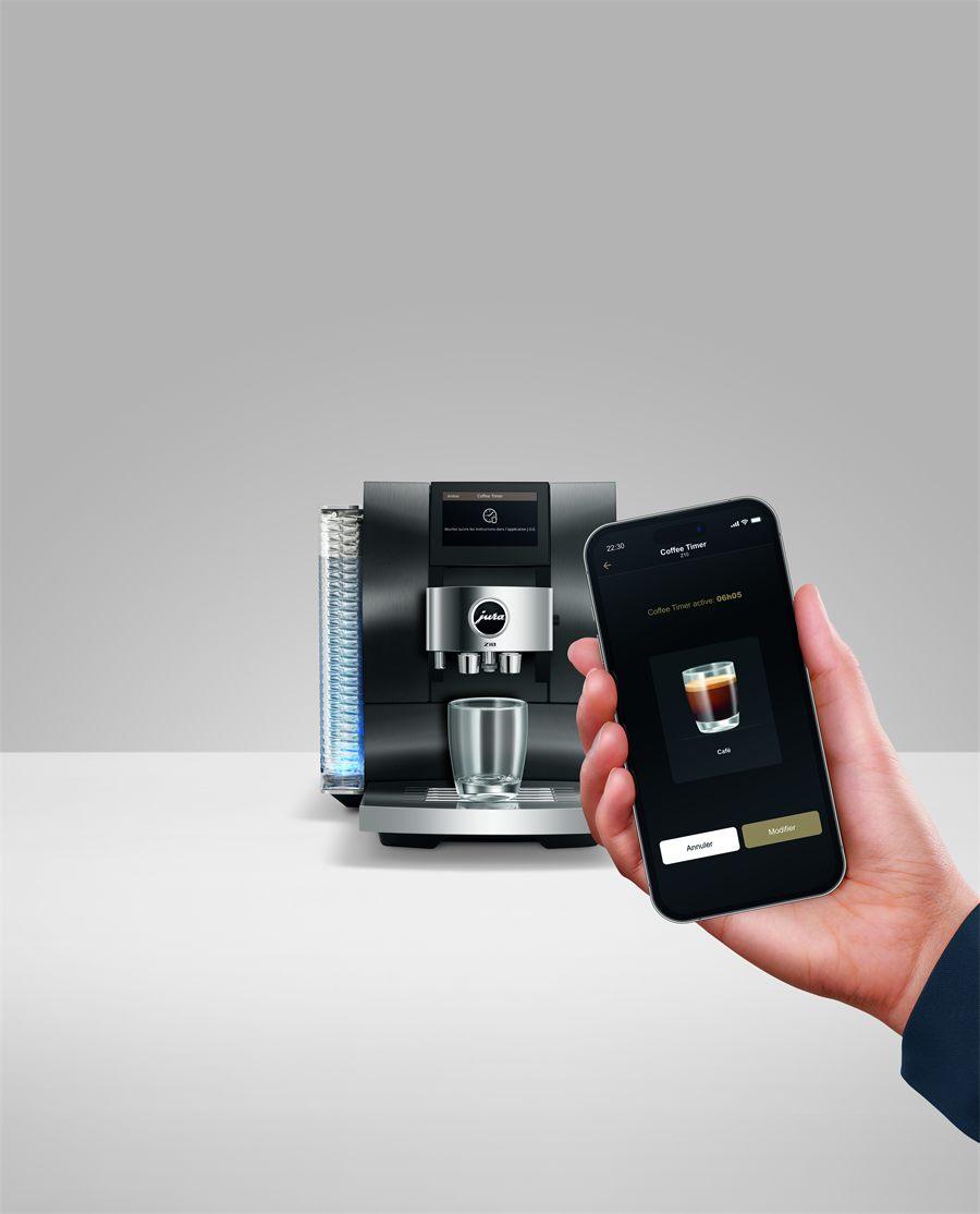 Le Coffee Timer de l'application JURA J.O.E. affiché sur un téléphone devant une machine