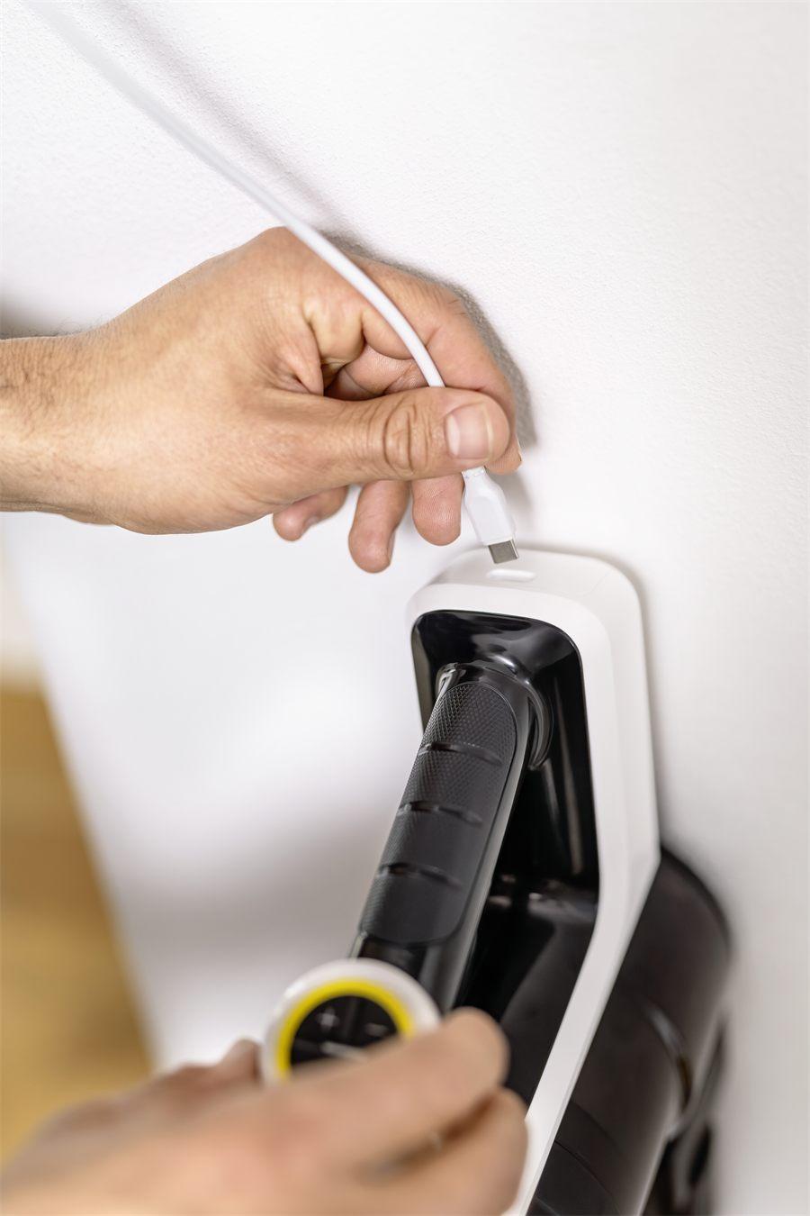 Câble USB-C branché sur un aspirateur balai Kärcher VCS 3 Nano posé sur son support mural