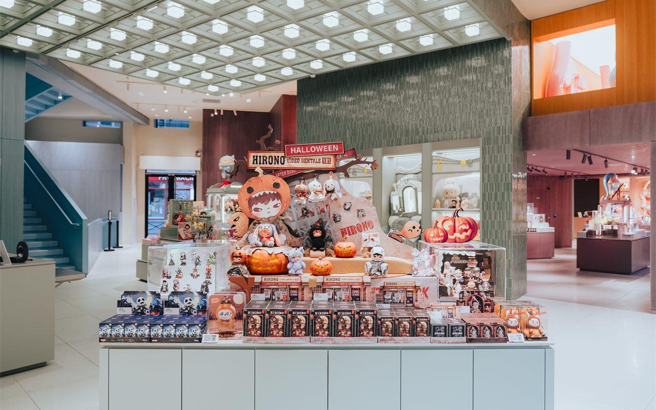 Îlot blanc couvert de boîtes surprises POP MART devant une paroi de pierre verte