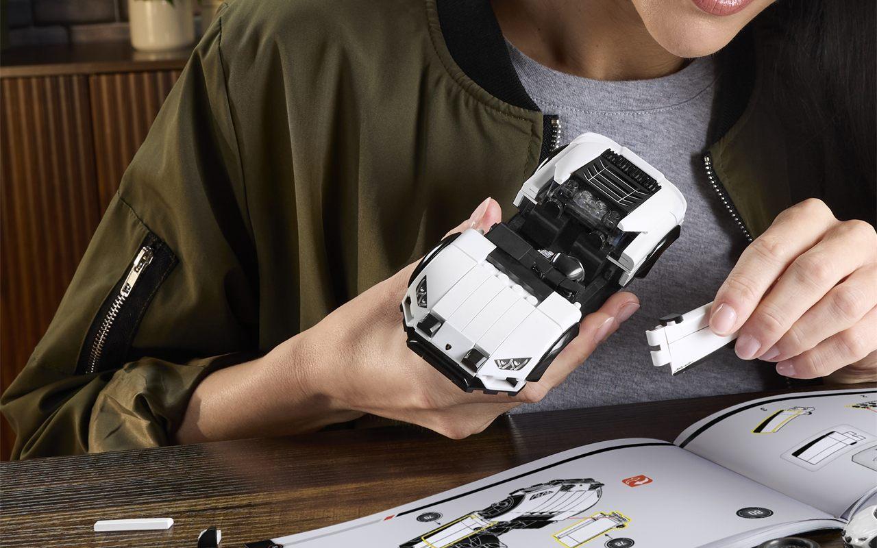 Une femme assemble le coffret Mattel Brick Shop Lamborghini Huracán Sterrato, la notice ouverte sur la table
