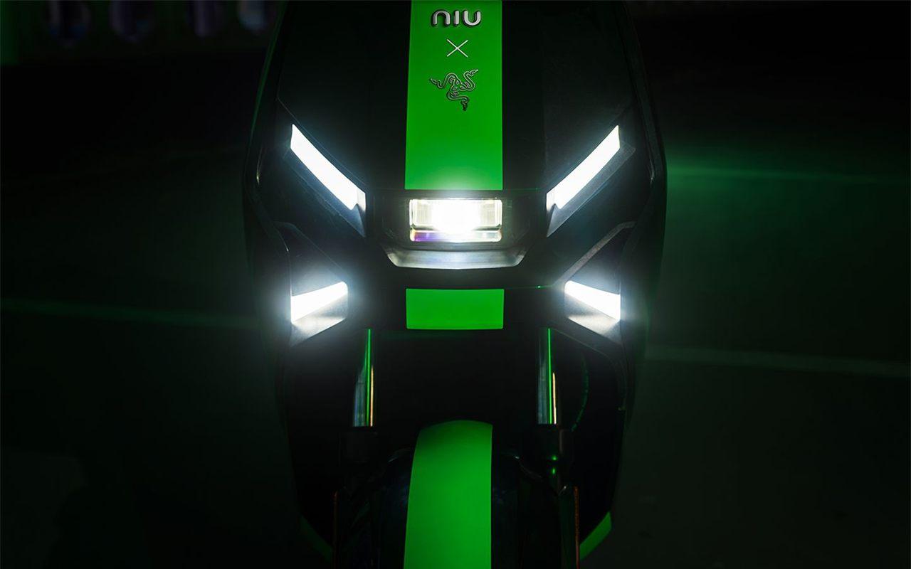 Optique avant en X du NIU FQiX x Razer, allumée, avec les logos NIU et Razer