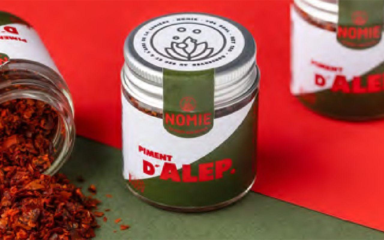 Pot de piment d'Alep Nomie et flocons rouges renversés sur fond vert