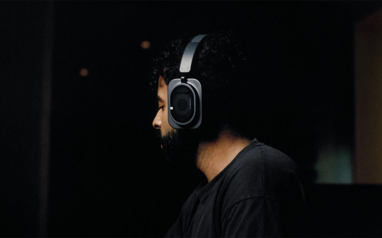 Un homme écoute au casque Nothing Headphone (1) Pro noir dans la pénombre d'un studio
