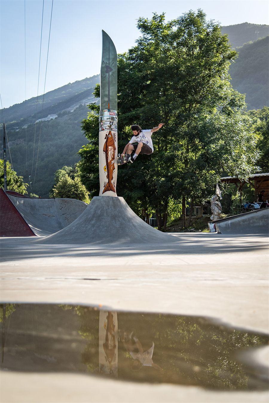 Un skateur saute devant le Volcano Opinel, reflété dans une flaque du skatepark