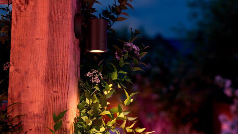 Spot extérieur Philips Hue Struana fixé sur un poteau au milieu de la végétation