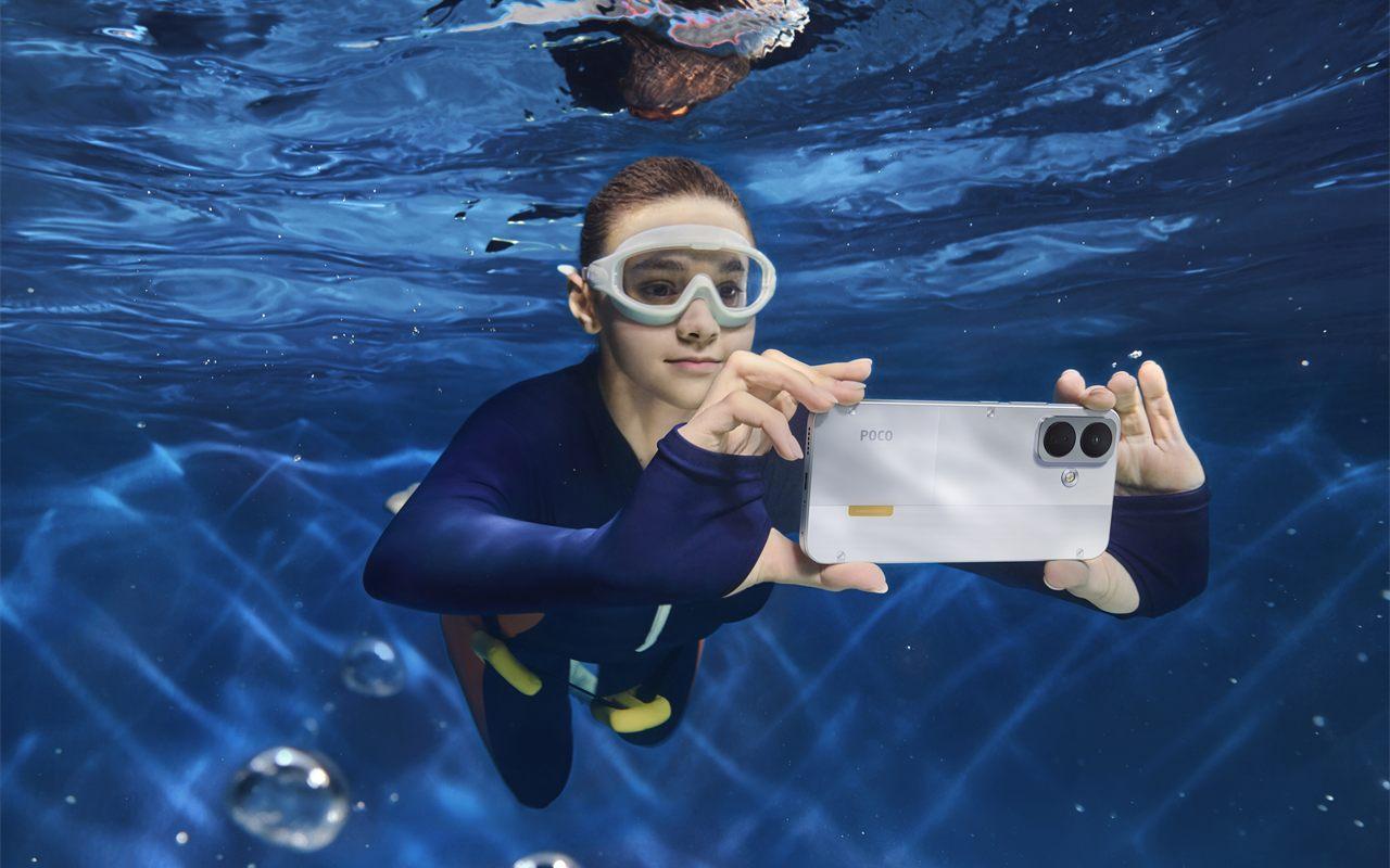 Une plongeuse photographie sous l'eau avec le POCO X8 blanc