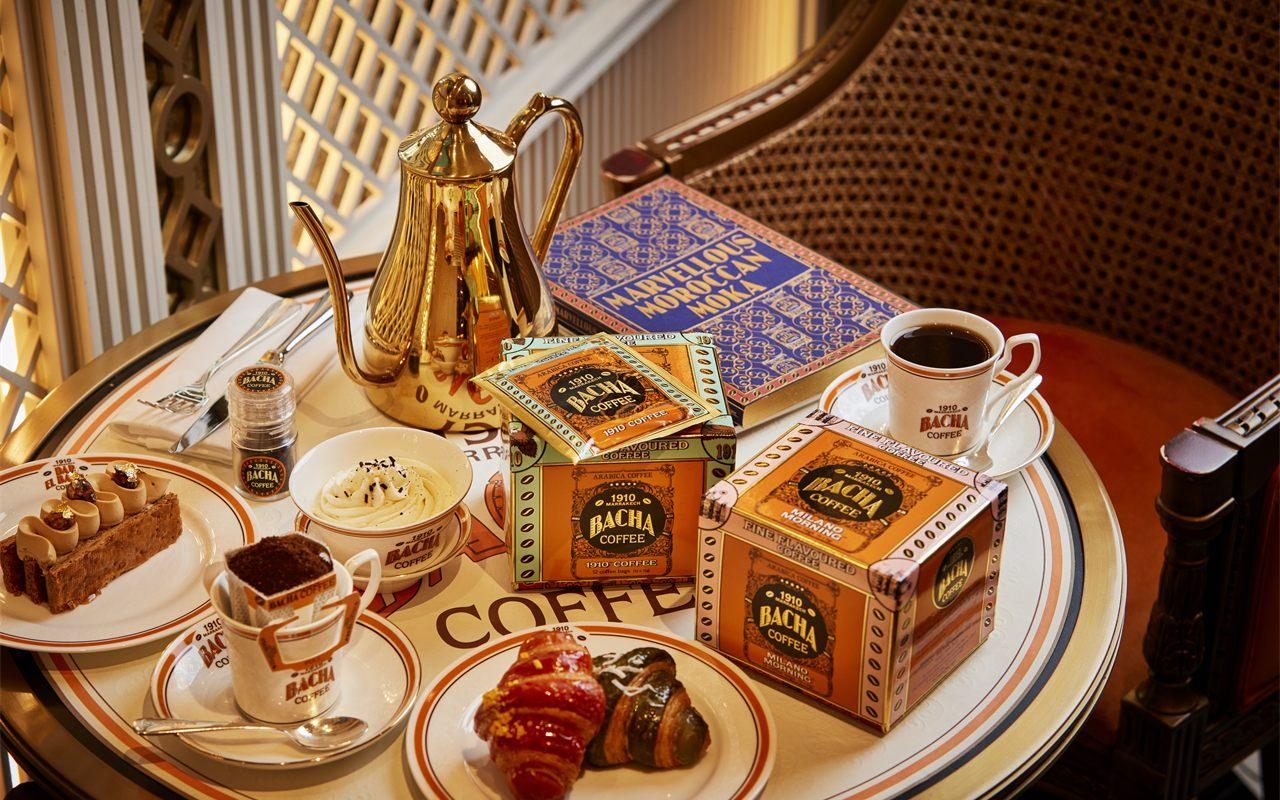 Théière dorée, coffrets et tasse Bacha Coffee dressés sur une table de salon
