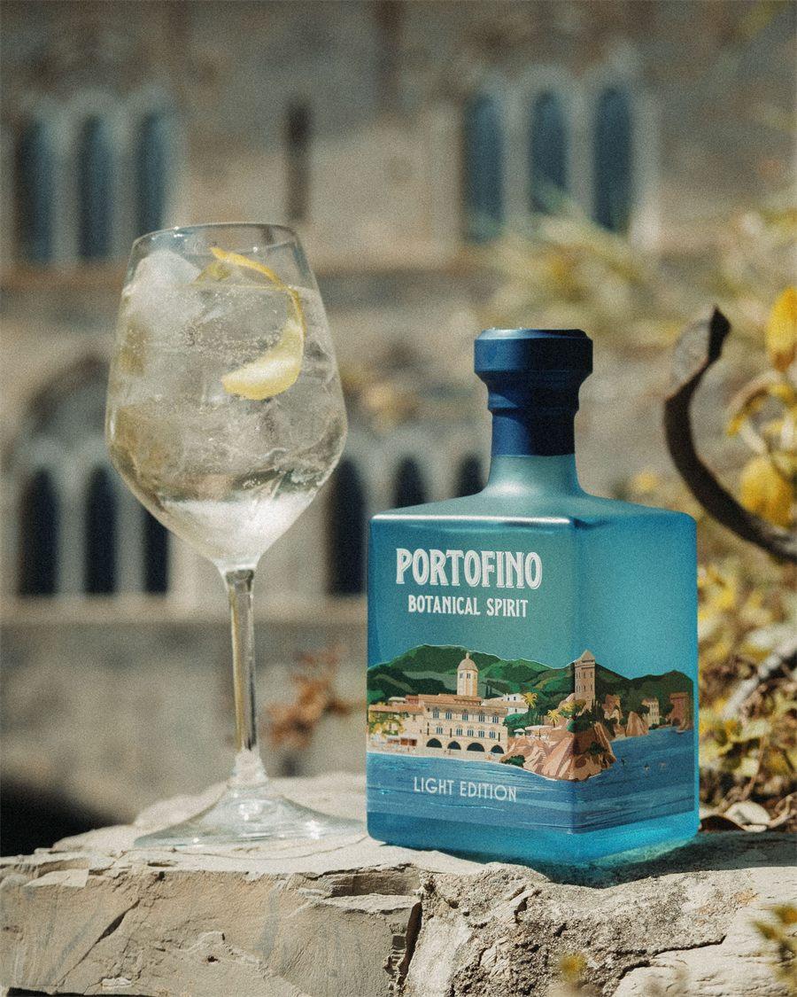 Verre à pied avec glaçons et zeste de citron devant la bouteille de Portofino Botanical Spirit