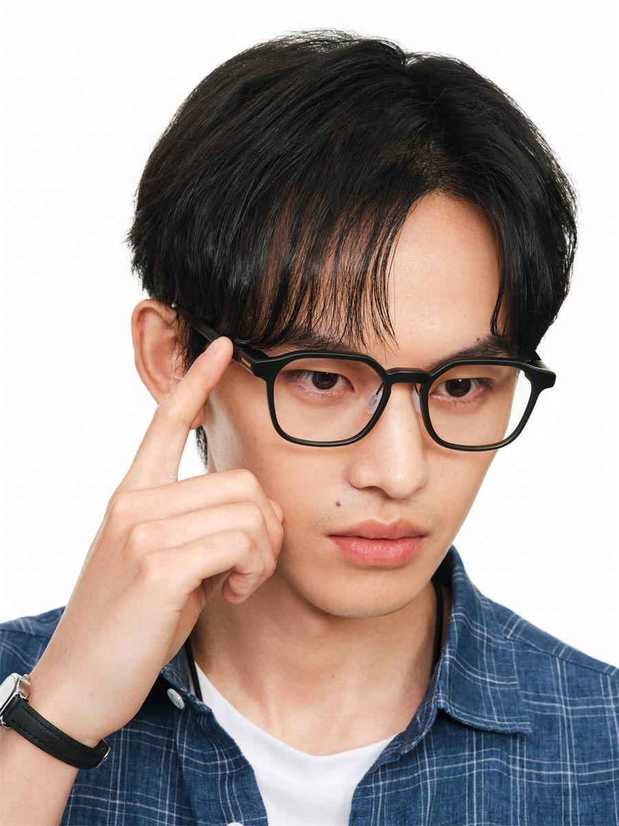Homme portant les lunettes RayNeo iO noires, doigt posé sur la branche