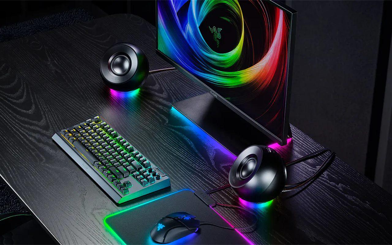 Un bureau de jeu éclairé par les enceintes Razer Mako X, clavier et écran allumés
